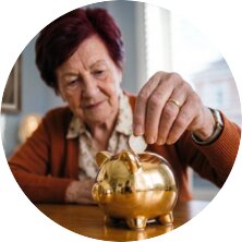 Eine alte Frau steckt Geld in ein Sparschwein